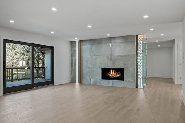 unfurnished living room with baseboards, recessed lighting, a tile fireplace, and wood finished floors