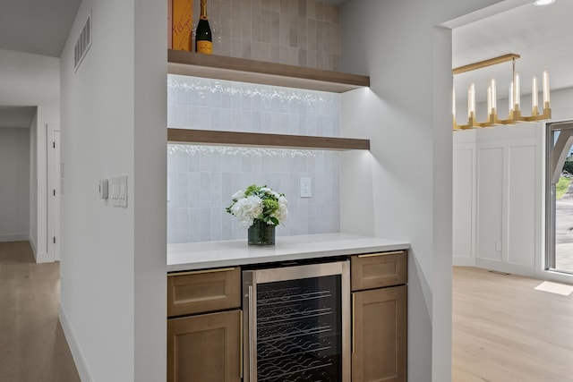 bar featuring visible vents, pendant lighting, wine cooler, light wood-style floors, and backsplash