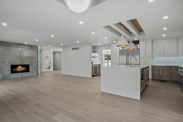 kitchen with light stone countertops, a tile fireplace, a sink, light wood finished floors, and stainless steel appliances