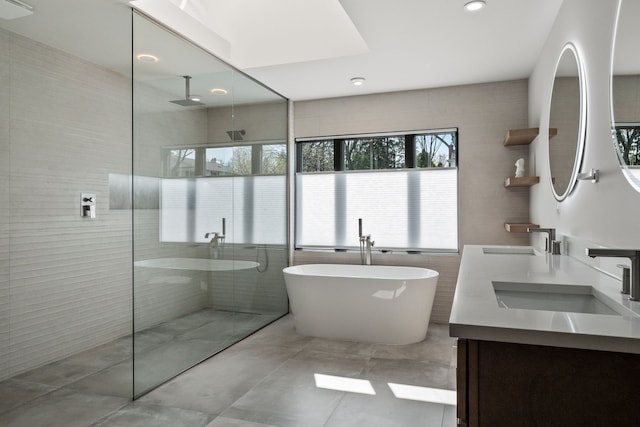 bathroom with tile walls, walk in shower, plenty of natural light, and a sink