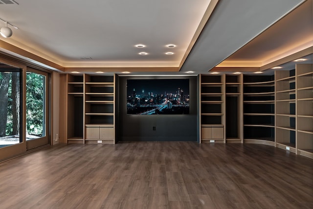cinema featuring visible vents, built in shelves, wood finished floors, and a raised ceiling