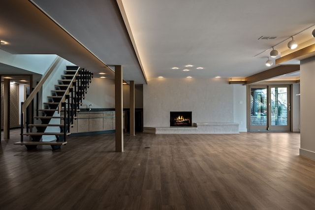 unfurnished living room with visible vents, stairs, dark wood-style floors, and a fireplace