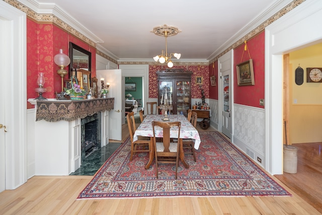 117 Bradley St, Romeo, MI 48065 - dining room featuring a chandelier, a fireplace, wainscoting, wallpapered walls, and wood finished floors