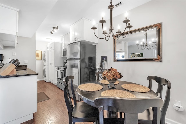 2993 Maplewood, Lake Orion, MI 48360 - dining space with visible vents, stacked washer and dryer, wood finished floors, baseboards, and a chandelier