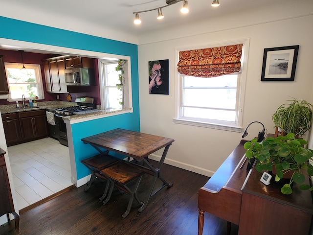 kitchen with stainless steel appliances, a sink, light wood finished floors, and dark brown cabinets