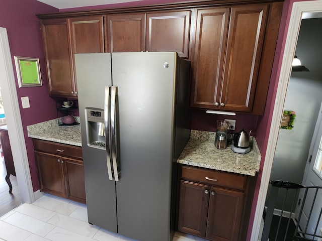 kitchen with stainless steel refrigerator with ice dispenser and light stone counters