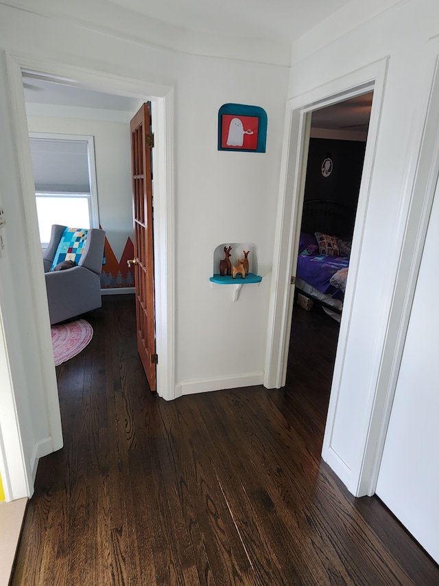 hallway featuring dark wood-style floors and baseboards