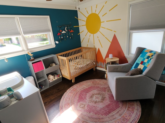 bedroom featuring wood finished floors, a nursery area, and a sink