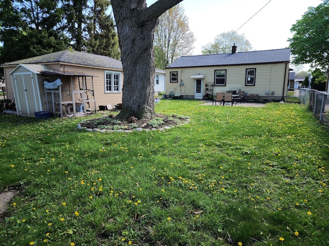 back of property with a patio area, an outdoor structure, a chimney, and a storage unit