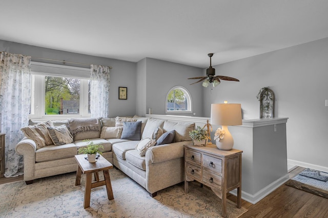 living area with ceiling fan, a wealth of natural light, wood finished floors, and baseboards