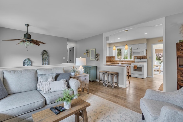 living room featuring light wood-style floors, ceiling fan, recessed lighting, and baseboards