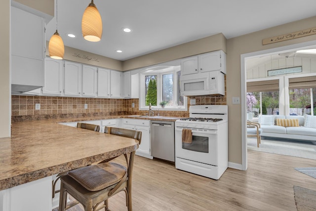 kitchen featuring light wood-style floors, white appliances, white cabinets, and a sink