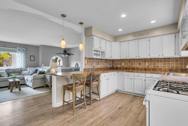 kitchen with white gas range, white cabinetry, recessed lighting, and a sink
