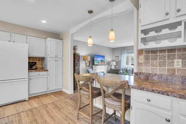 kitchen with decorative backsplash, white cabinets, light wood-style floors, freestanding refrigerator, and recessed lighting