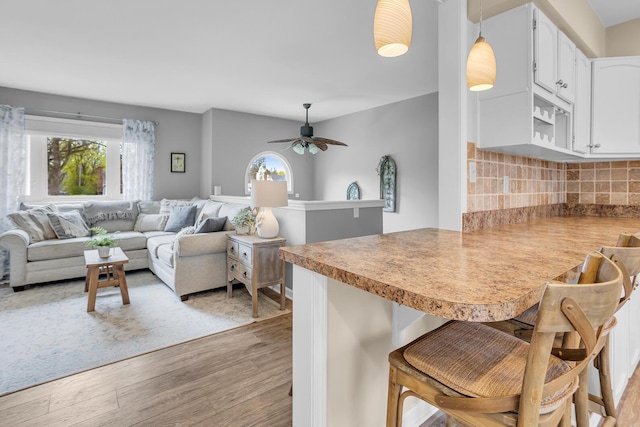 kitchen featuring a wealth of natural light, a breakfast bar area, a peninsula, and light wood-style flooring