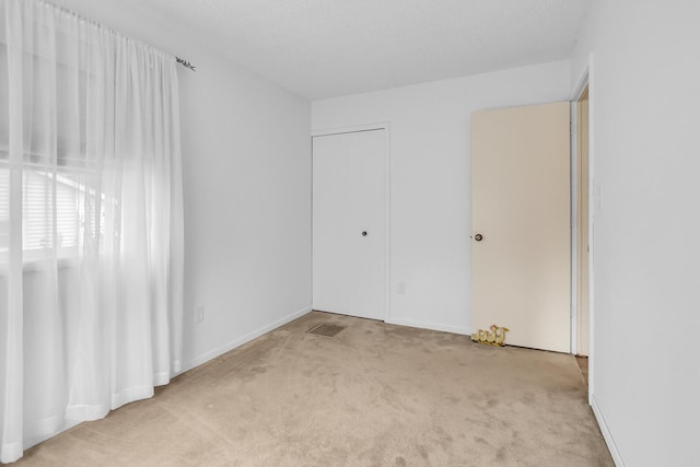 unfurnished bedroom with visible vents, carpet floors, and baseboards
