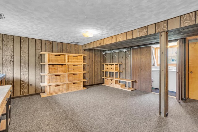finished below grade area with washer and clothes dryer, wooden walls, a textured ceiling, and carpet flooring