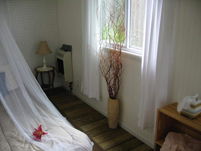 bedroom with heating unit, wood finished floors, and baseboards