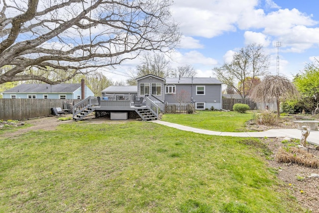 back of house featuring fence, stairway, a deck, and a lawn
