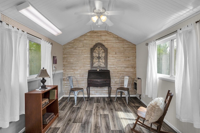 living area with wood finished floors, heating unit, vaulted ceiling, wood walls, and ceiling fan