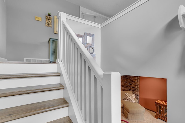 stairway featuring visible vents, ornamental molding, a high ceiling, and carpet