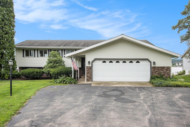tri-level home with driveway, a front yard, brick siding, and a garage