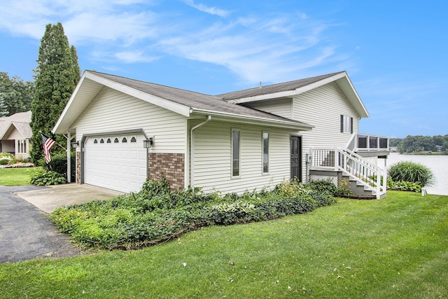 view of side of property featuring a lawn, driveway, stairs, brick siding, and an attached garage