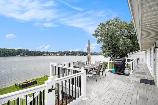 deck featuring outdoor dining area and a water view