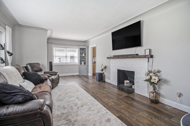 living room with baseboards, a fireplace with flush hearth, and dark wood-type flooring