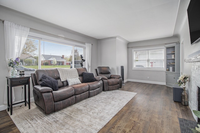 living area with baseboards, plenty of natural light, dark wood-type flooring, and a fireplace