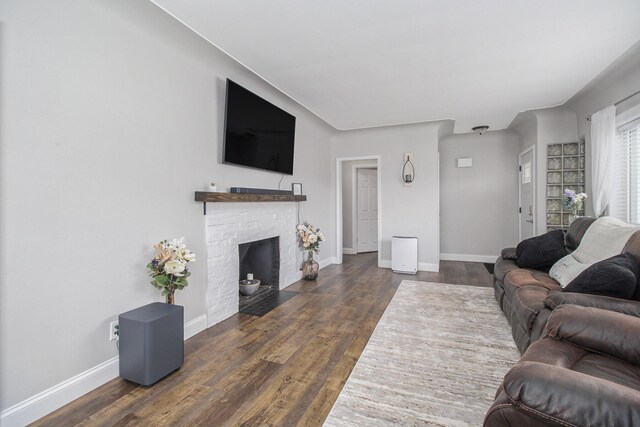 living area featuring baseboards, a fireplace with flush hearth, and wood finished floors