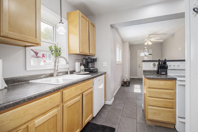 kitchen featuring light brown cabinetry, dark countertops, ceiling fan, a sink, and white appliances