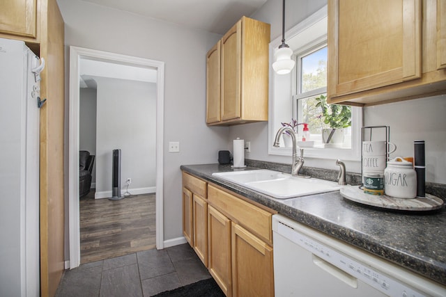 kitchen with decorative light fixtures, white dishwasher, dark countertops, a sink, and baseboards