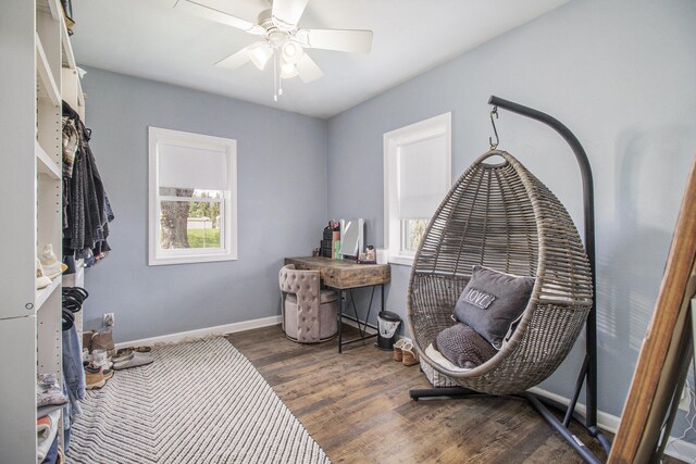 living area with baseboards, a ceiling fan, and wood finished floors