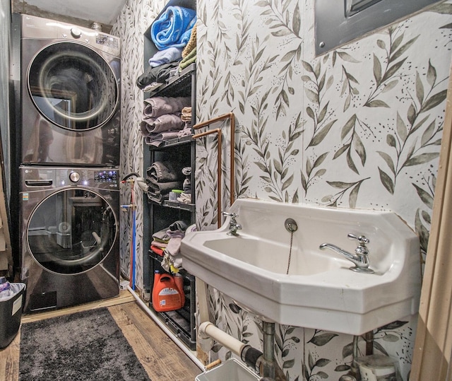 bathroom featuring a sink, stacked washer / dryer, and wood finished floors