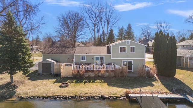 back of house featuring a lawn, a storage unit, a fire pit, and an outbuilding
