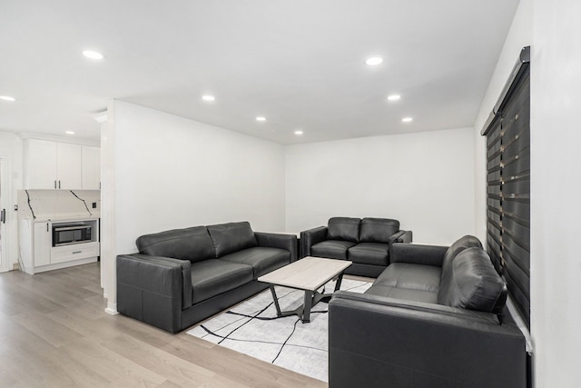 living room with recessed lighting, a large fireplace, and light wood-style flooring