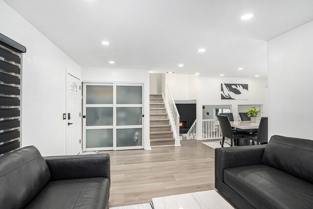 living room with recessed lighting, light wood finished floors, and stairs