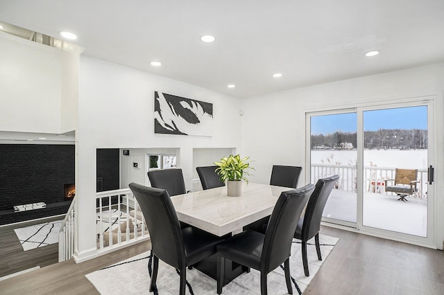 dining space featuring recessed lighting, wood finished floors, and a lit fireplace