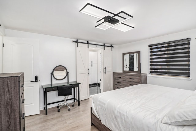 bedroom with a barn door and light wood-style floors