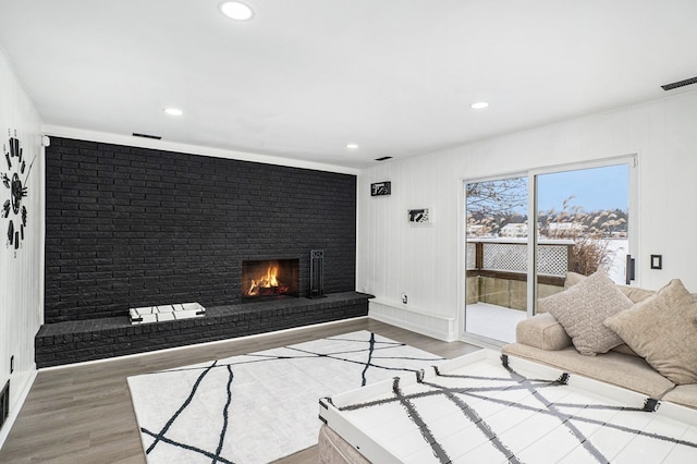 living area with visible vents, baseboards, recessed lighting, a brick fireplace, and wood finished floors