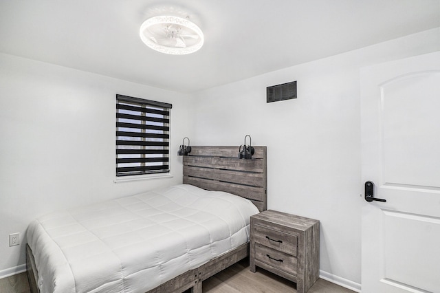 bedroom with wood finished floors, visible vents, and baseboards