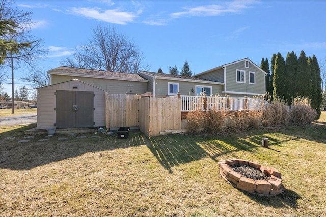 rear view of house featuring a deck, an outbuilding, a storage shed, an outdoor fire pit, and a yard