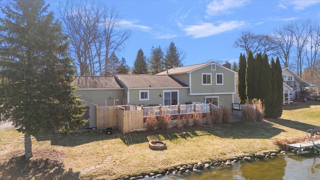 rear view of house with a wooden deck, a yard, a fire pit, and a chimney
