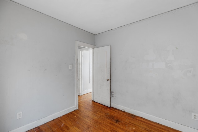 empty room with baseboards and wood-type flooring
