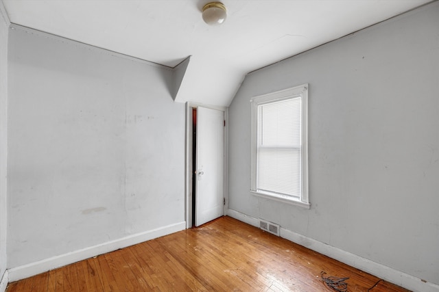 additional living space featuring visible vents, baseboards, lofted ceiling, and light wood-type flooring
