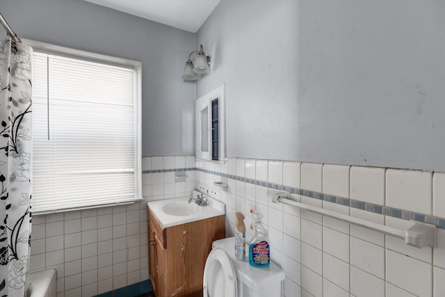 bathroom with plenty of natural light, wainscoting, vanity, and tile walls