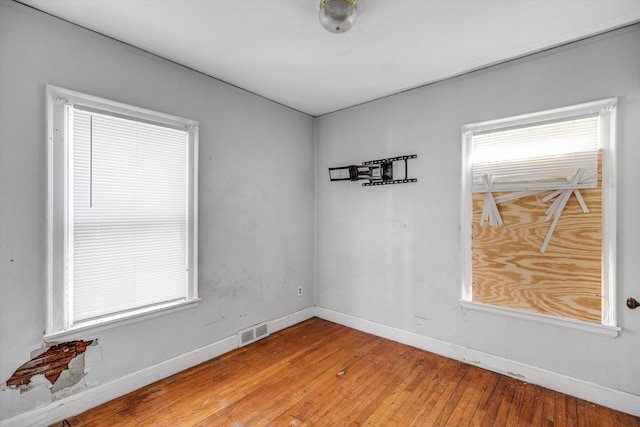 spare room with baseboards, visible vents, and hardwood / wood-style floors