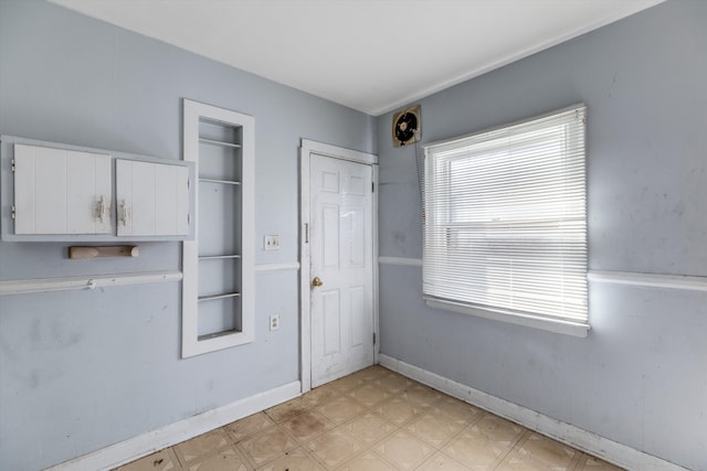interior space featuring light floors, baseboards, built in shelves, and white cabinetry