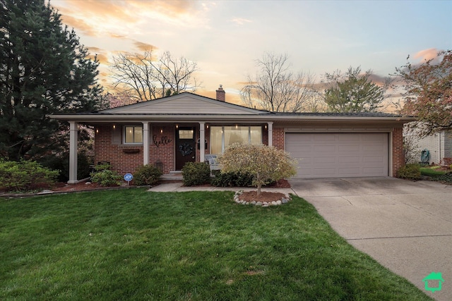 view of front facade featuring a chimney, a yard, brick siding, concrete driveway, and an attached garage